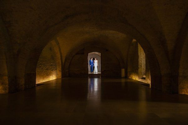 Fotografía en el Real Alcázar de Sevilla en las bodegas donde la pareja de novios están mirándose.