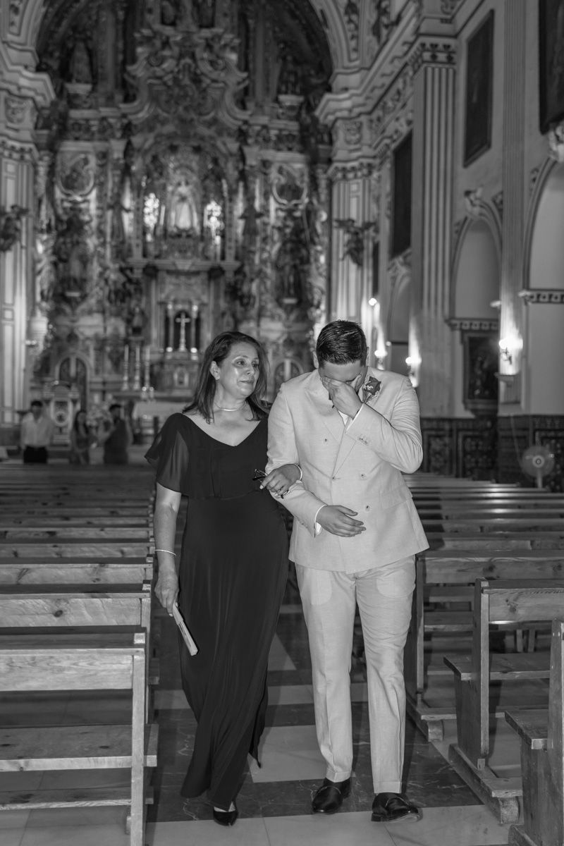 Fotografía del novio llorando al ver a la novia en la entrada de la iglesia de Sevilla junto a la madrina